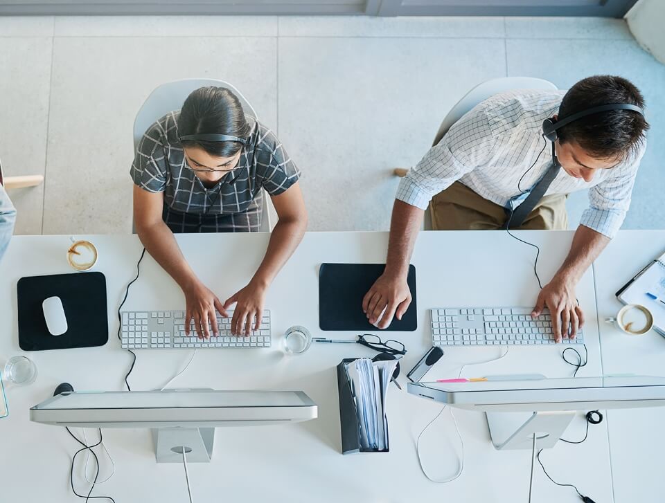 to personer med headset arbejder på computere
