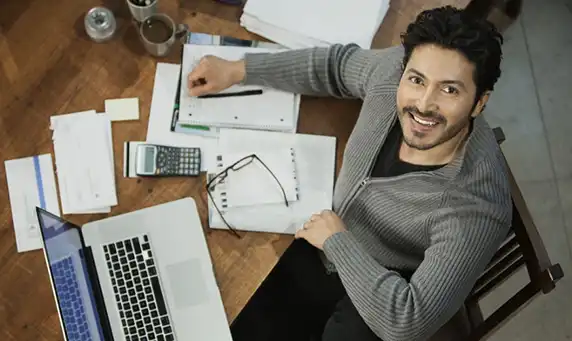 mand, der sidder ved et skrivebord med en bærbar computer